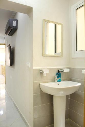 a white bathroom with a sink and a mirror at Apart al hoceima in Al Hoceïma