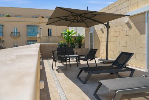 a patio with a table and chairs and an umbrella at Casa Lina Suites in Sliema