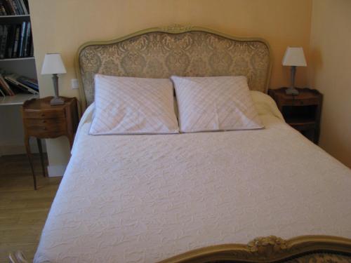 a bed with two pillows on it with two tables at Gîte l'Hermine in Val Couesnon