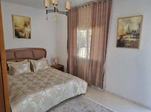 a bedroom with a bed and a window at home byrsa in Douar ech Chott