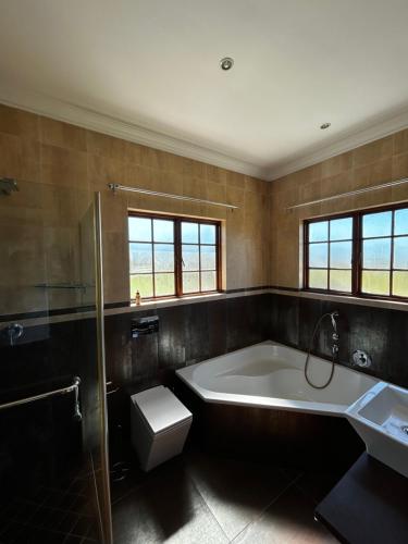 a bathroom with a tub and a toilet and a sink at Acacia House in Winterton