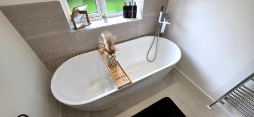 a bathroom with a toilet and a bath tub with a window at Stoney Lane Cottage in Wakefield