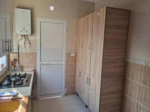 a kitchen with wooden cabinets and a stove at home byrsa in Douar ech Chott