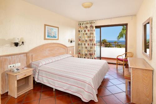 a bedroom with a bed and a desk and a window at Apartamentos Masaru in Puerto de la Cruz