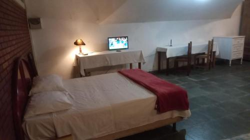 a bedroom with a bed and a table and a television at Pousada Vila Bela in Poços de Caldas