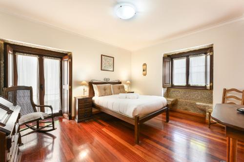 a bedroom with a bed and a desk and windows at Casa da Galheira with Swimming Pool by Sé Apartamentos in Vilela