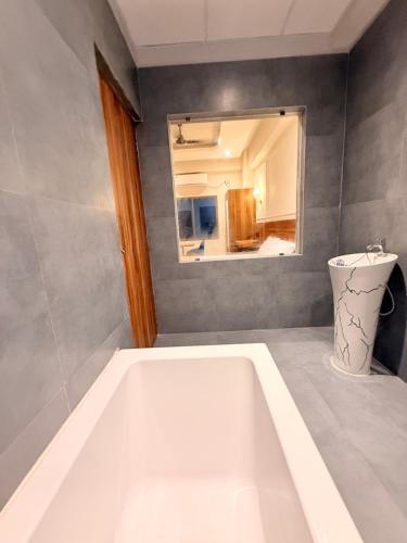 a white bath tub in a bathroom with a mirror at Rishaan Regency in Silchar