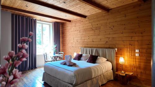 a bedroom with a bed and a wooden wall at Hotel La Font Vineuse & Spa in Saint-Pierre-dʼArgençon