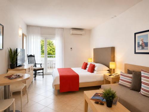 a hotel room with a bed and a living room at Waterman Svpetrvs Resort - All Inclusive in Supetar