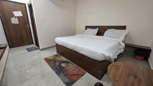 a bedroom with a bed with white sheets and a table at Hotel dream house 2 in Murādnagar