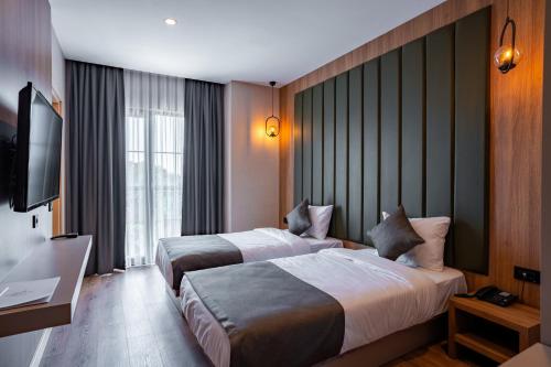 a hotel room with two beds and a flat screen tv at Perast City Hotel in Antalya