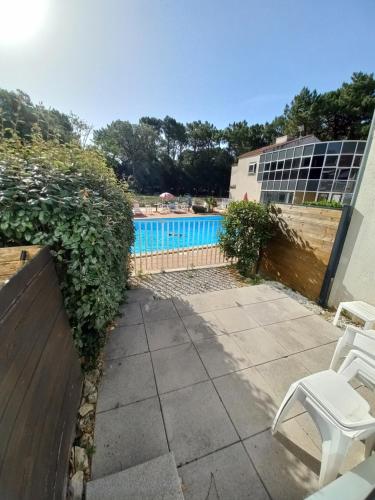 a patio with a white chair and a swimming pool at Domaine jard mer in Jard-sur-Mer