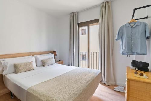 a bedroom with a bed and a shirt hanging on a rack at Rambla de Mar Apartments by Blossom Hotels in Barcelona