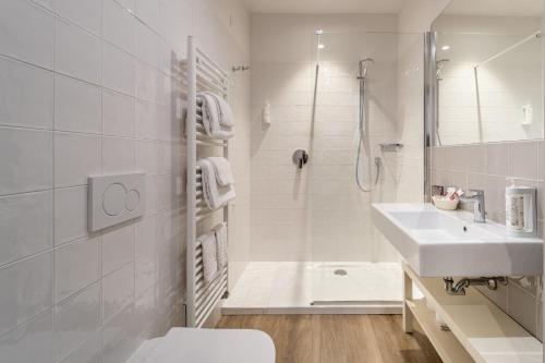 a white bathroom with a toilet and a sink at Hotel Quarcino in Como