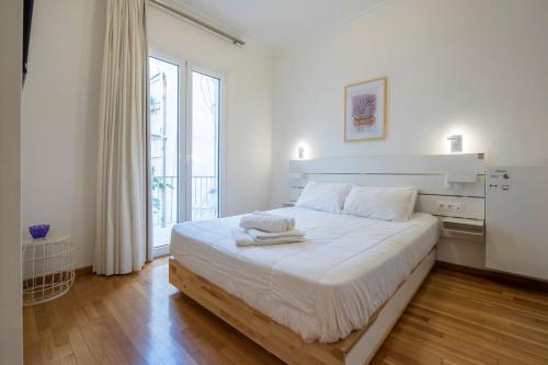 a white bedroom with a large bed and a window at Syntagma Gem 2 in Athens