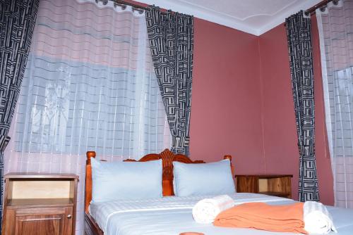 two beds in a bedroom with pink walls at Larry Homestay in Kapchorwa