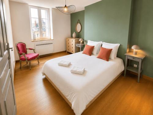 a bedroom with a large white bed and a red chair at Aux loges du théâtre in Moulins