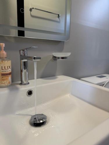 a bathroom sink with water running from a faucet at Paradise Beachfront Chalet Rooms Borsh in Borsh