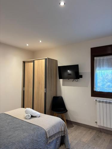 a bedroom with a bed and a cabinet and a television at Apartamentos Fuente La Pipa in Avín
