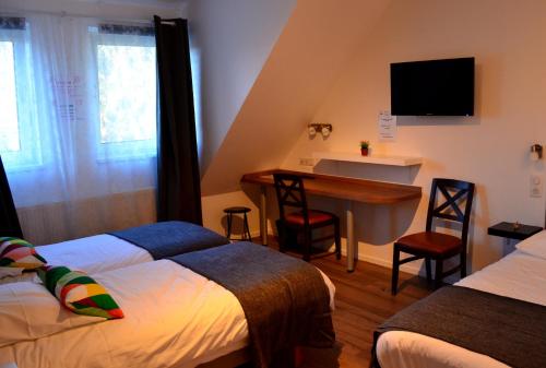 a hotel room with two beds and a desk and a television at Hôtel Restaurant La Couronne in Roppenheim