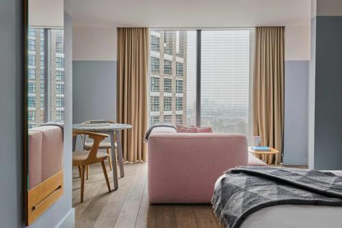 a bedroom with a bed and a table and a room with windows at Leman Locke in London