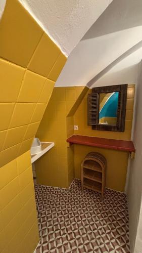 a yellow room with a fireplace and a tv at Longo maï in Vallon-Pont-dʼArc