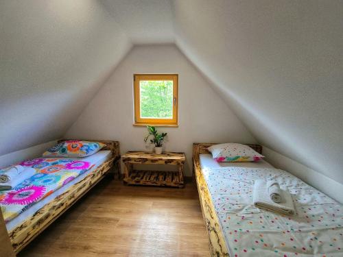 two beds in a attic room with a window at Gorsko zavetje Cottage in Soča