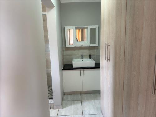 a bathroom with a sink and a mirror at Kairos Guest House in Maseru