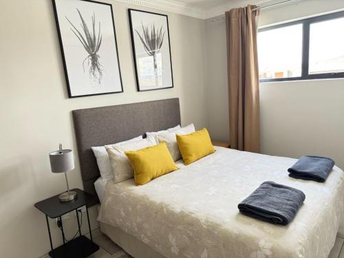 a bedroom with a bed with yellow pillows and a window at Kairos Guest House in Maseru