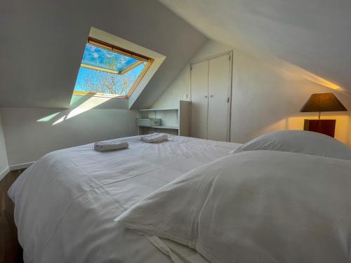 a bedroom with a white bed with a window at Ty Heole House in Plouézec