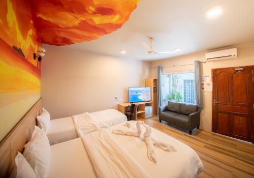a bedroom with two beds and a couch and a television at Villa Crescenta in Ukulhas