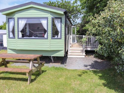 a green house with a picnic table and a bench at Sarnfaen Static - Uk52097 in Llanddwywe