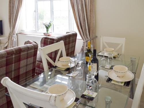 a glass table with chairs and wine bottles on it at Rudda Farm Cottage - Uk2492 in Staintondale
