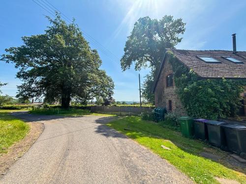 an empty road next to a house with trash cans at The Boyne Arms Cottage in Burwarton