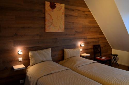 two beds in a room with wooden walls at Hôtel Restaurant La Couronne in Roppenheim