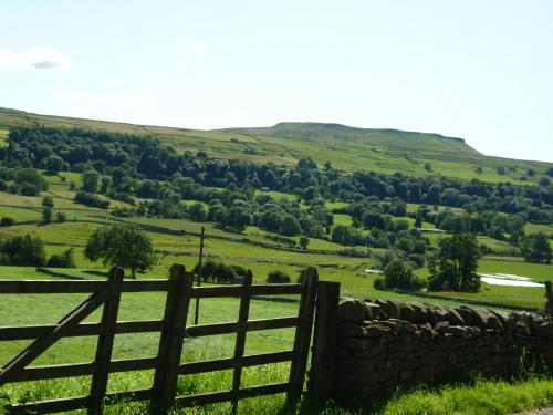 a wooden gate in a field with a fence at Bloomer's Bothy in Askrigg