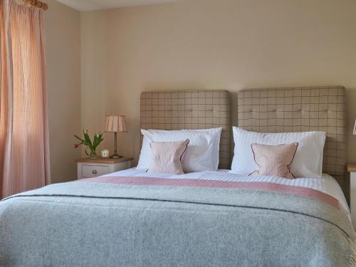a bedroom with a large bed with white pillows at Hungate Garden Cottage in Pickering