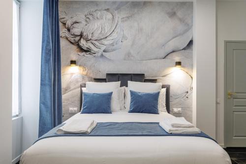 a bedroom with a large bed with blue pillows at Maison Astéria in Nice