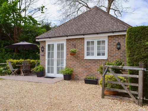 a small brick house with a table and an umbrella at Petit Knowle in Cuckfield
