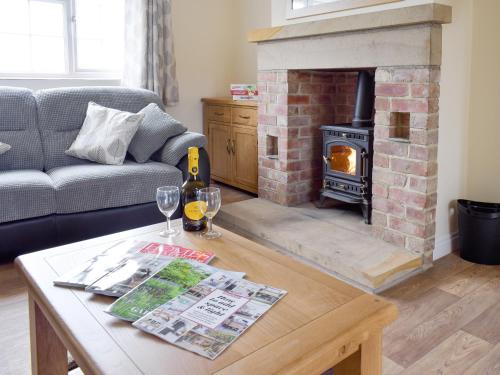 a living room with a fireplace and a table with wine glasses at Rudda Farm House - Uk2491 in Staintondale