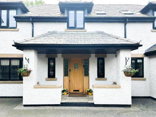 a white house with a wooden door and windows at Castlebar in Little Singleton