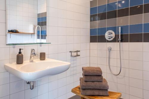 a bathroom with a sink and a shower with towels at ParelDuyn in Oostkapelle