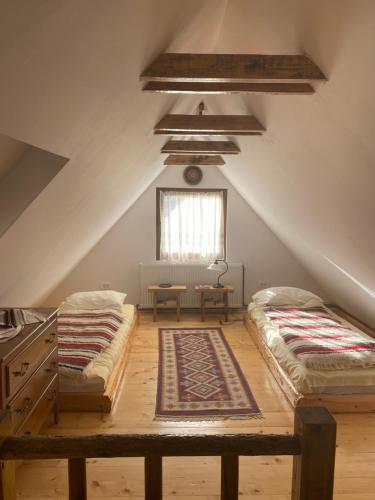 a attic room with two beds and a window at Căsuța Anei in Rîmeţi-Valea Inzelului