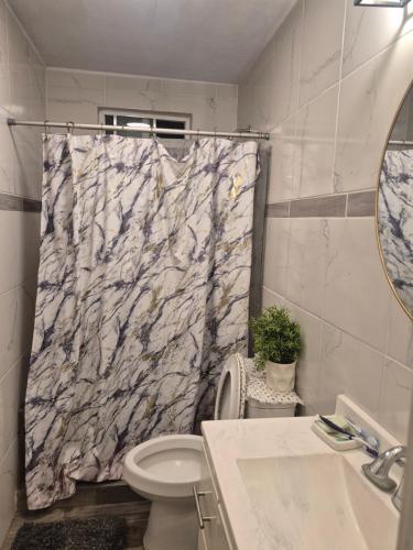 a bathroom with a marble shower curtain and a toilet at La casa de la Playa in Primo Tapia