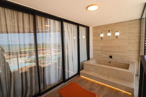 a bathroom with a tub and a large window at Tauá Hotel e Convention João pessoa in João Pessoa