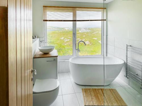 a bathroom with a tub and a sink and a window at Grianan in Eriskay