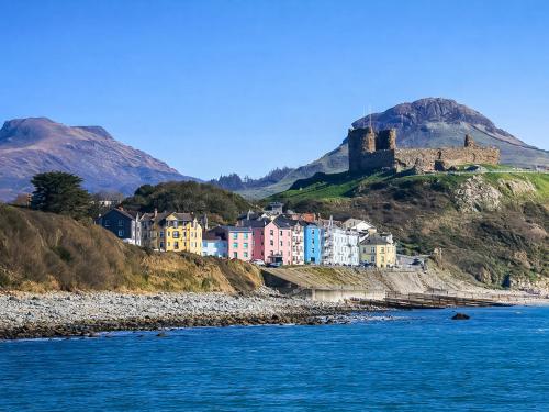 a town on a hill next to the water with a castle at Glan Y Mor - Uk52092 in Criccieth