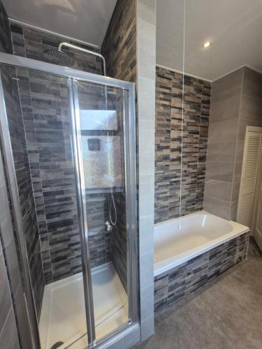 a bathroom with a shower and a tub at Miners Lamp Apartment in Easington