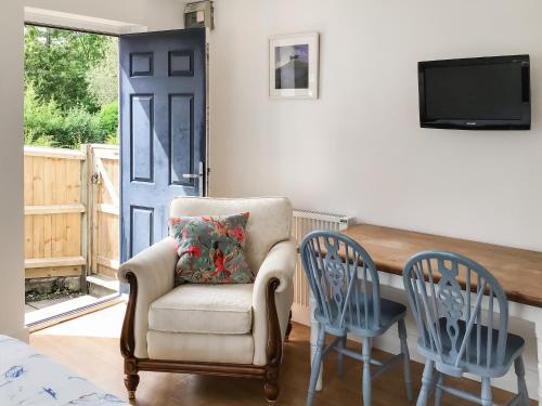 a living room with a chair and a tv at Farthings - 19292 in Bridport
