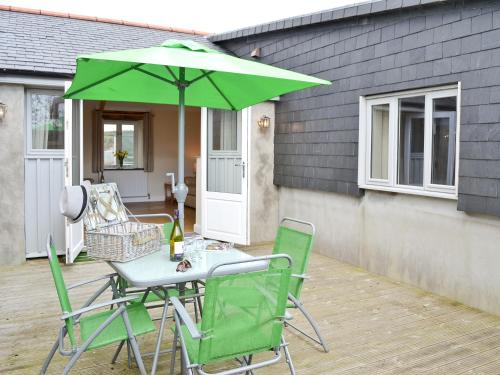 a table and chairs with a green umbrella on a patio at Tresidder Barn in Constantine